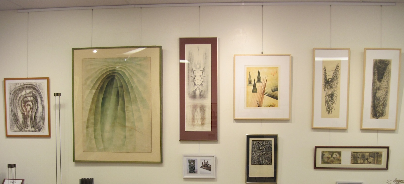 Wide view of paintings and prints by modernist Harry Bertoia hung on picture hanging system