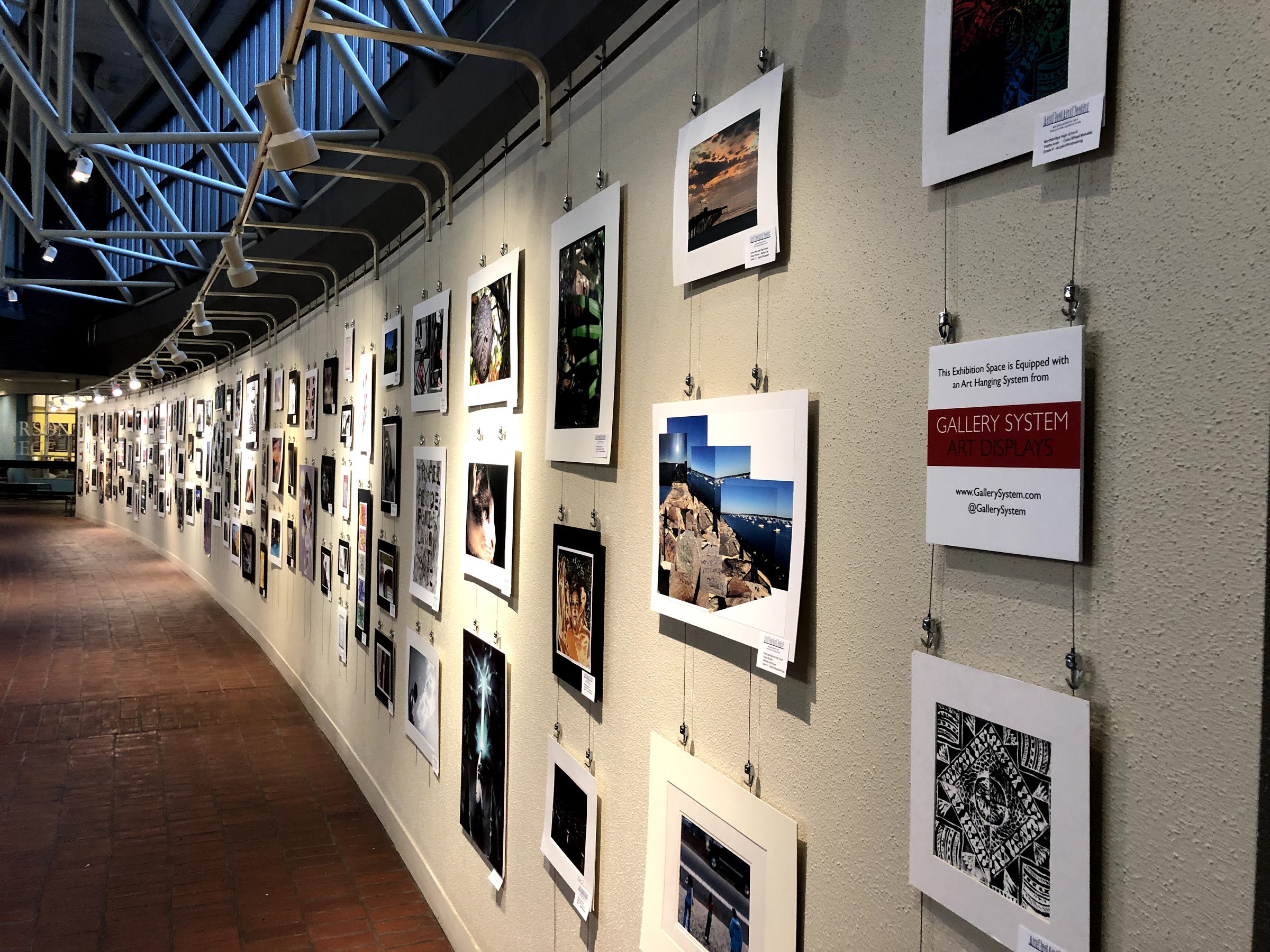Student artworks displayed in public building using picture hanging system