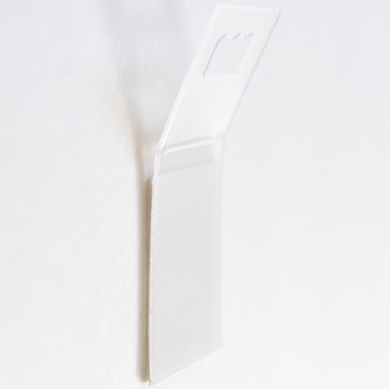 Adhesive hanger attached to back of artwork for picture hanging system use