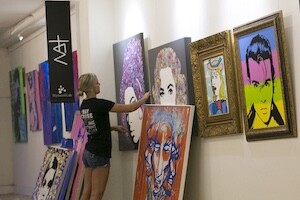 Woman installing art on gallery wall using picture hanging system