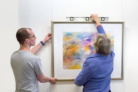 Man and Woman hanging art with a Picture Hanging System 