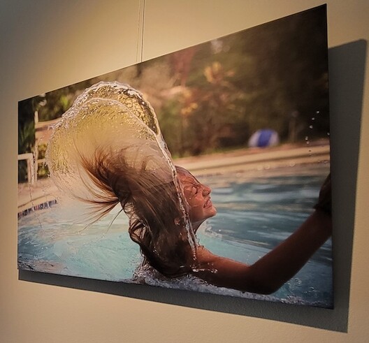 Photograph of person in swimming pool displayed on art hanging system