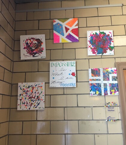 Student art displayed in corridor corner using art hanging system