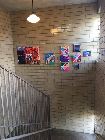 Vertical view of art display in school stairwell using picture hanging system