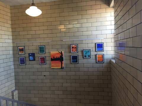 Wide view of art display in school stairwell using picture hanging system