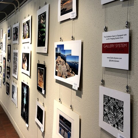 Student artworks displayed in public building using picture hanging system